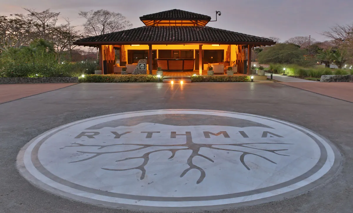 Rythmia's open-air lodge at dusk, with the Rythmia emblem set into the stone plaza